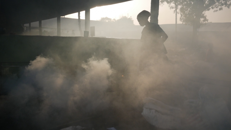woman tends smoky wood fire in shea-butter processing plant